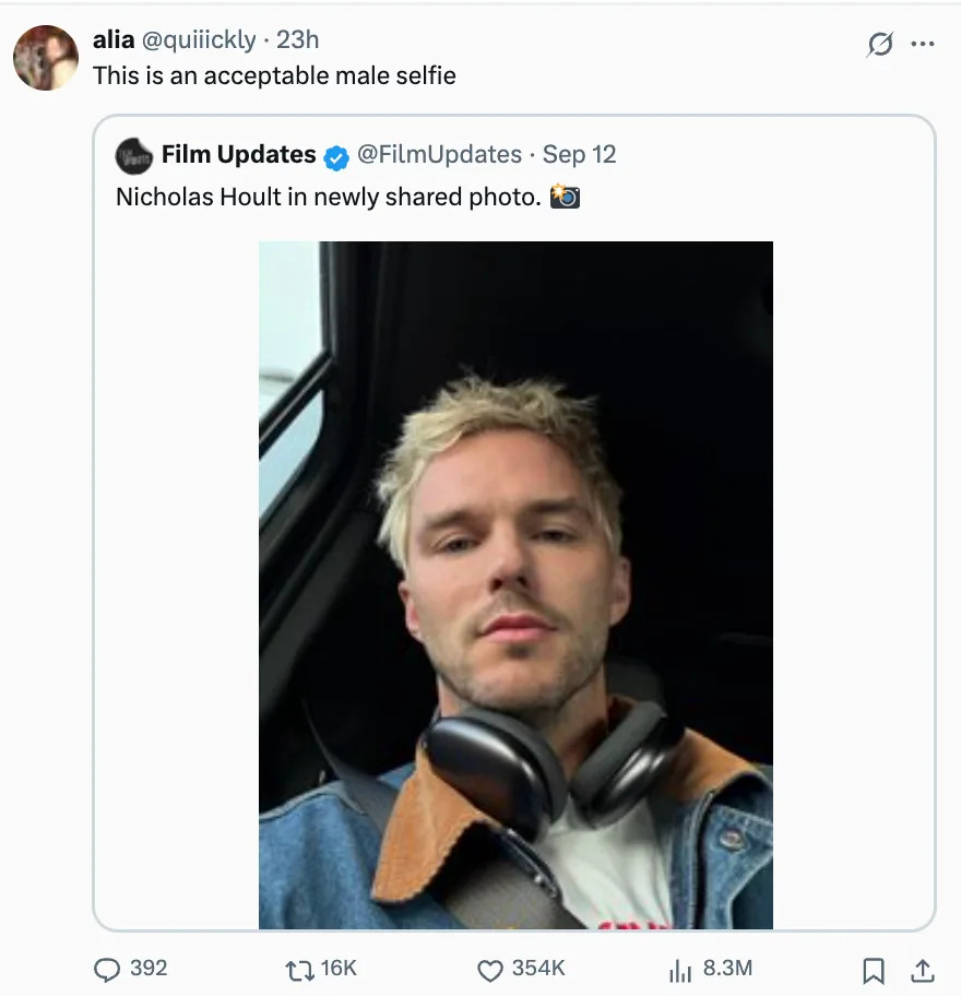 Nicholas Hoult taking a selfie in a casual outfit, wearing headphones around his neck, inside a vehicle