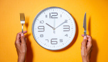 A clock as if it were a plate of food next to a hands holding fork and knife.