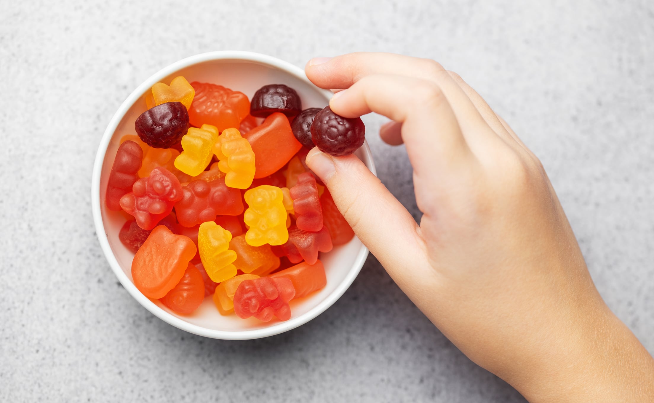 Chewable gummy bears vitamins and supplements.  A girl holds a gummy bear vitamins in her hands.