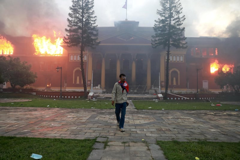 A man is draped in the Nepal national flag as a fire rages through the president's office in Kathmandu on Tuesday, a day after a police crackdown on demonstrations over social media prohibitions and corruption by the government. Photograph: Anup Ojha/AFP via Getty Images     