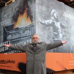 Art dealer John Brandler, the owner of "Season's Greetings" by street artist Banksy, poses as the artwork, sealed in a crate, is removed from a retail unit at Ty'r Orsaf in Port Talbot February 8, 2022, before being stored at an undisclosed location. (Photo Geoff Caddick / AFP) (Photo GEOFF CADDICK/AFP via Getty Images)