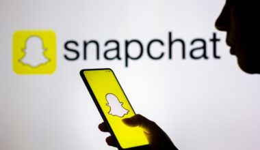 In this photo illustration, a woman's silhouette holds a smartphone with the Snapchat logo displayed on the screen and in the background.