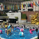 Grownups and children play in Joel Mesler's pool party-themed installation at 30 Rockefeller Park Plaza.