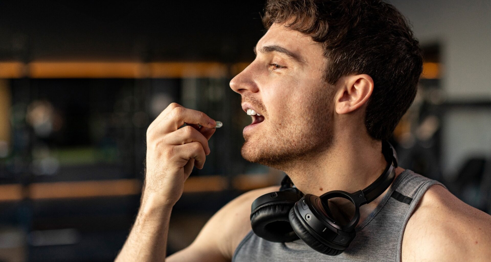 Sportive man taking supplement capsule,