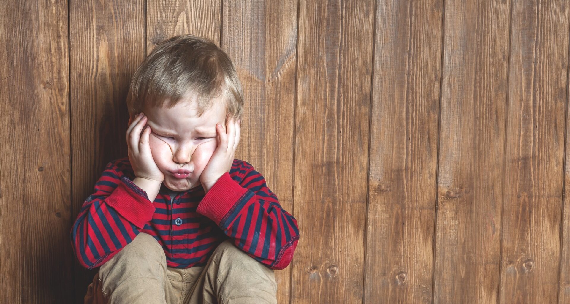 Stressed child covering ears and scrunching face