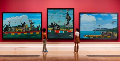 Three paintings hang on a wall in a museum. 