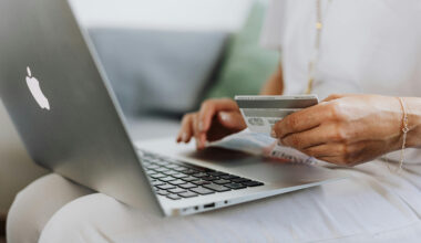 Person using a MacBook and holding a credit card