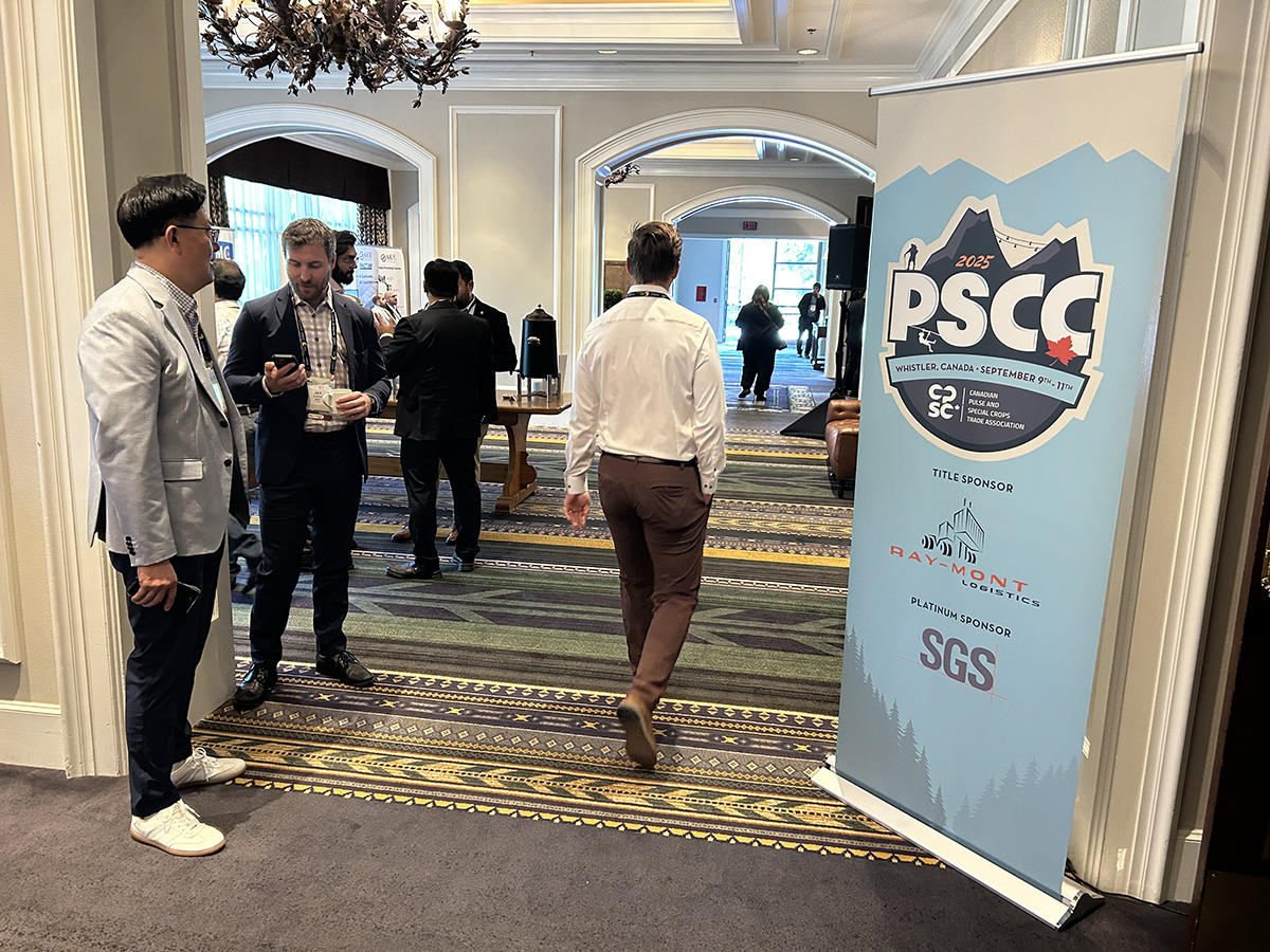 Delegates mingle in the doorway of a large meeting room with a large