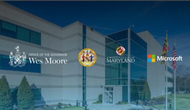 Exterior of a modern building with large glass windows and landscaped surroundings. Overlaid logos include the Office of the Governor (Wes Moore), the State of Maryland, the University of Maryland, and Microsoft—suggesting a collaborative initiative between government, academia, and technology sectors