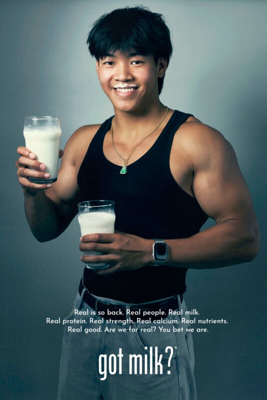 A smiling young man in a black tank top holds two large glasses of milk. White text at the bottom reads, "got milk?" with a message about the benefits of real milk above it.