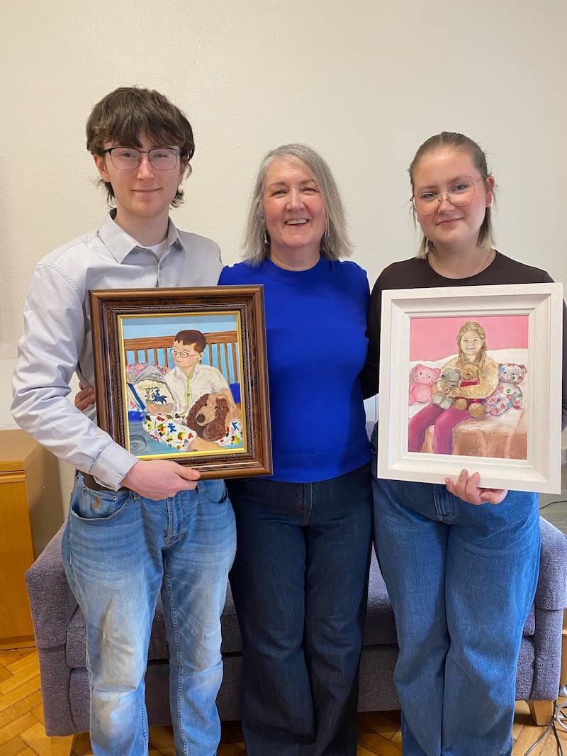 Billy and Frankie Gillespie with their mother Aedín. They are holding paintings of themselves painted by their late father Frank while he was in the hospice