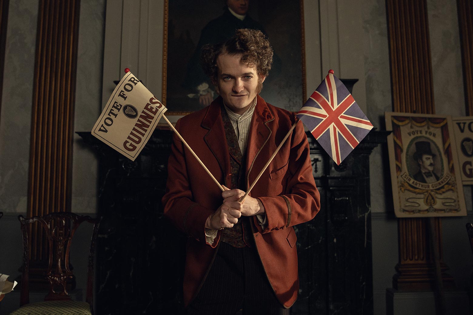 A Victorian man holding two crossed flags in a scene from the show.