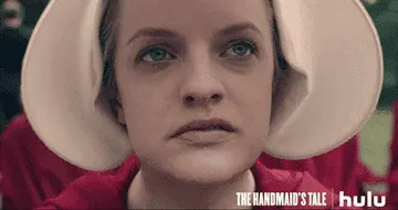Close-up of a woman wearing a white bonnet, looking solemn. "The Handmaid's Tale" logo appears in the corner