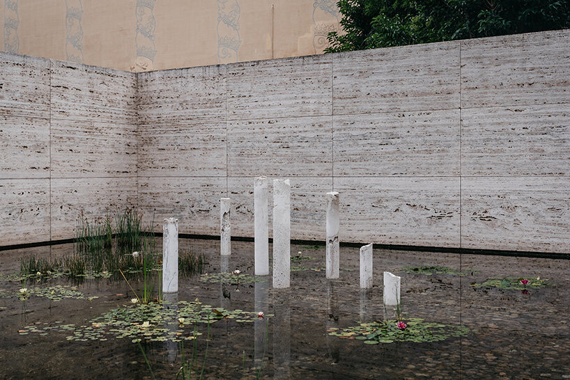concrete sculptures surface from the pond of mies van der rohe's barcelona pavilion