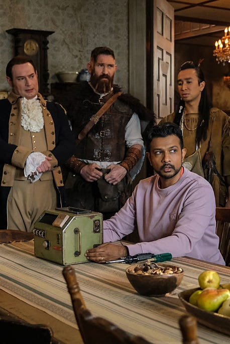 jay sitting at long wood table with a ghost trap box  pictured (l r):brandon scott jones as isaac, devan chandler long as thorfinn, utkarsh ambudkar as jay, zaragoza as sasappis jay sitting at long wood table with a ghost trap box pictured (l r):brandon scott jones as isaac, devan chandler long as thorfinn, utkarsh ambudkar as jay, zaragoza as sasappis