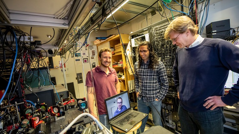 Dolev Bluvstein, Harry Levine (on the laptop), Sepehr Ebadi and Mikhail Lukin, on right, standing next to their neutral atom quantum computer, on left.