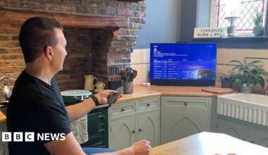 Man with goatee beard in dark shirt in front of a hedge