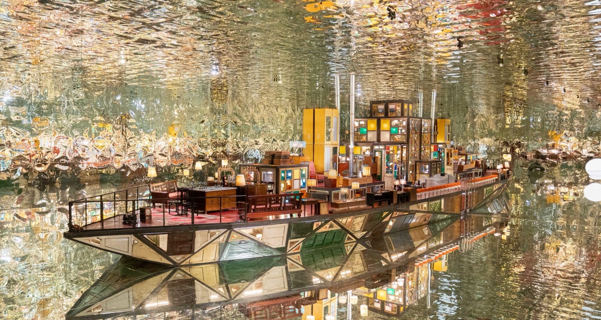 a large-scale installation by Song Dong in the shape of a boat within a fully reflective room, using found wooden window frames, color-coated glass, lamps, furniture, and other knick-knacks