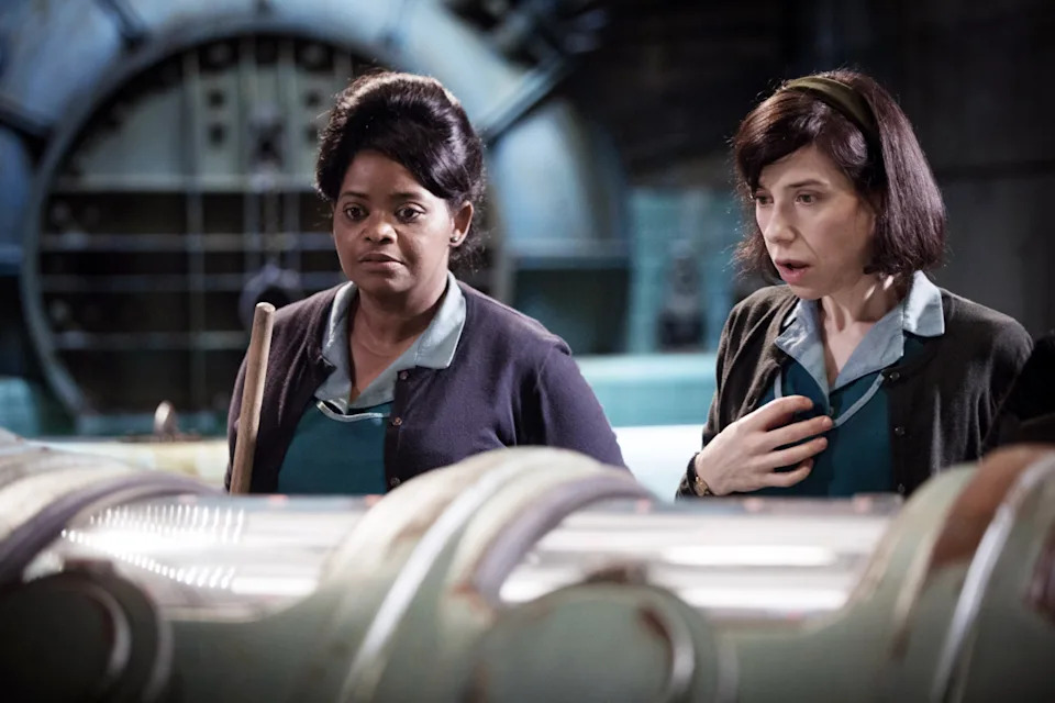 Two women in a vintage setting, wearing uniforms from the mid-20th century, look intently at something off-camera