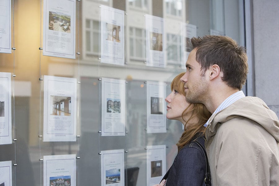 A couple look at properties in an estate agent window