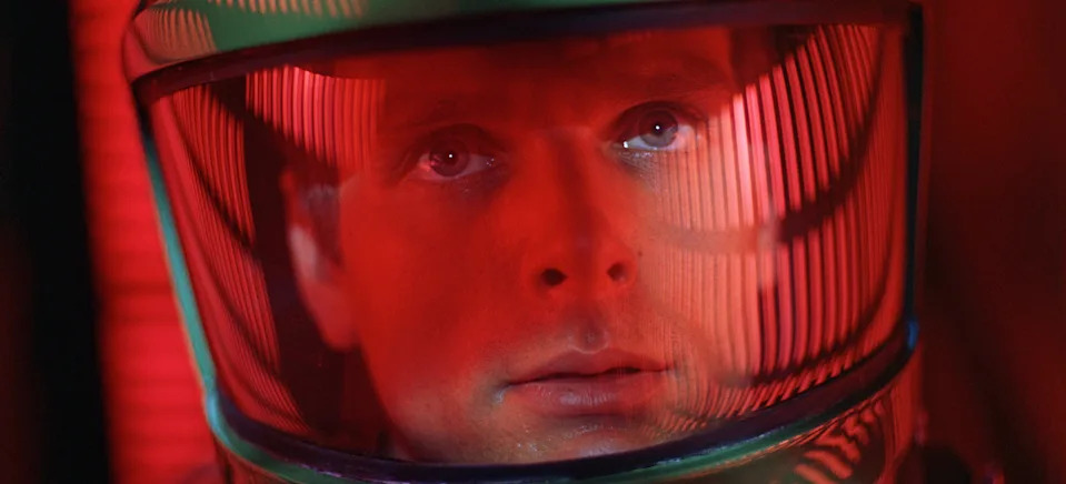 Person in a space helmet with a reflective visor, focused expression, from a sci-fi movie scene