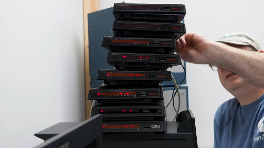 A number of black 56 Kbps dial-up modems stacked on top of eachother, red lights blinking.