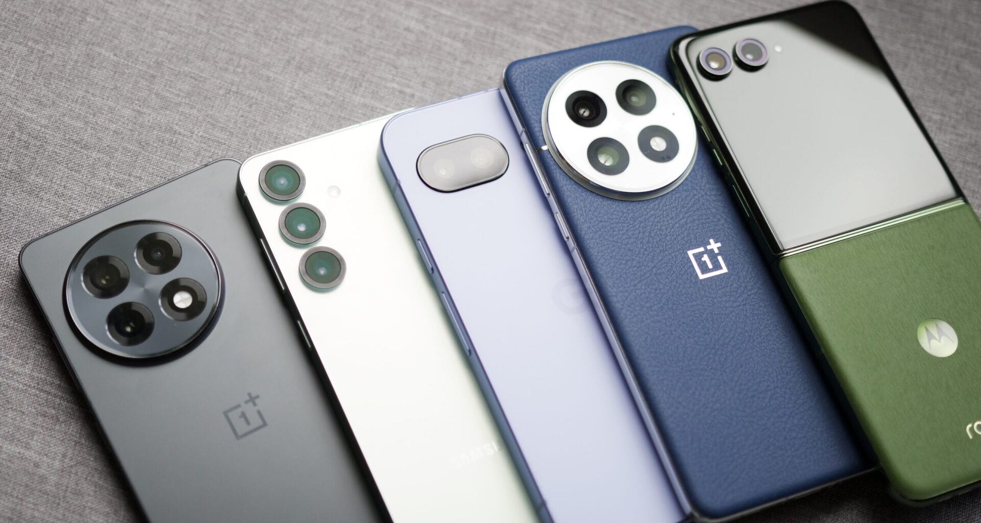 The OnePlus 13R, Galaxy S25, Pixel 9a, OnePlus 13, and Motorola Razr Plus (2024) are laying next to each other.