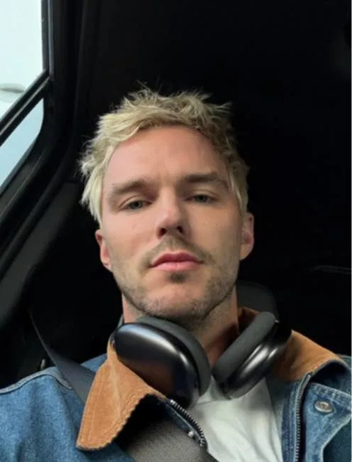 Nicholas Hault with short hair wearing denim jacket and headphones, seated in a car