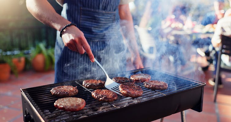Man turning burgers on a grill.