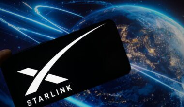 An image of the Starlink logo on a phone, with Earth and satellites in the background (gettyimages-2224910960)