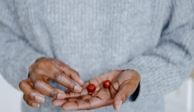 A close up of a person&apos;s hand holding two red gummy supplements. They are wearing a light grey sweater.