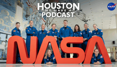 HWHAP Ep. 402. The 2025 Class of Astronaut Candidates poses behind the NASA Worm logo.