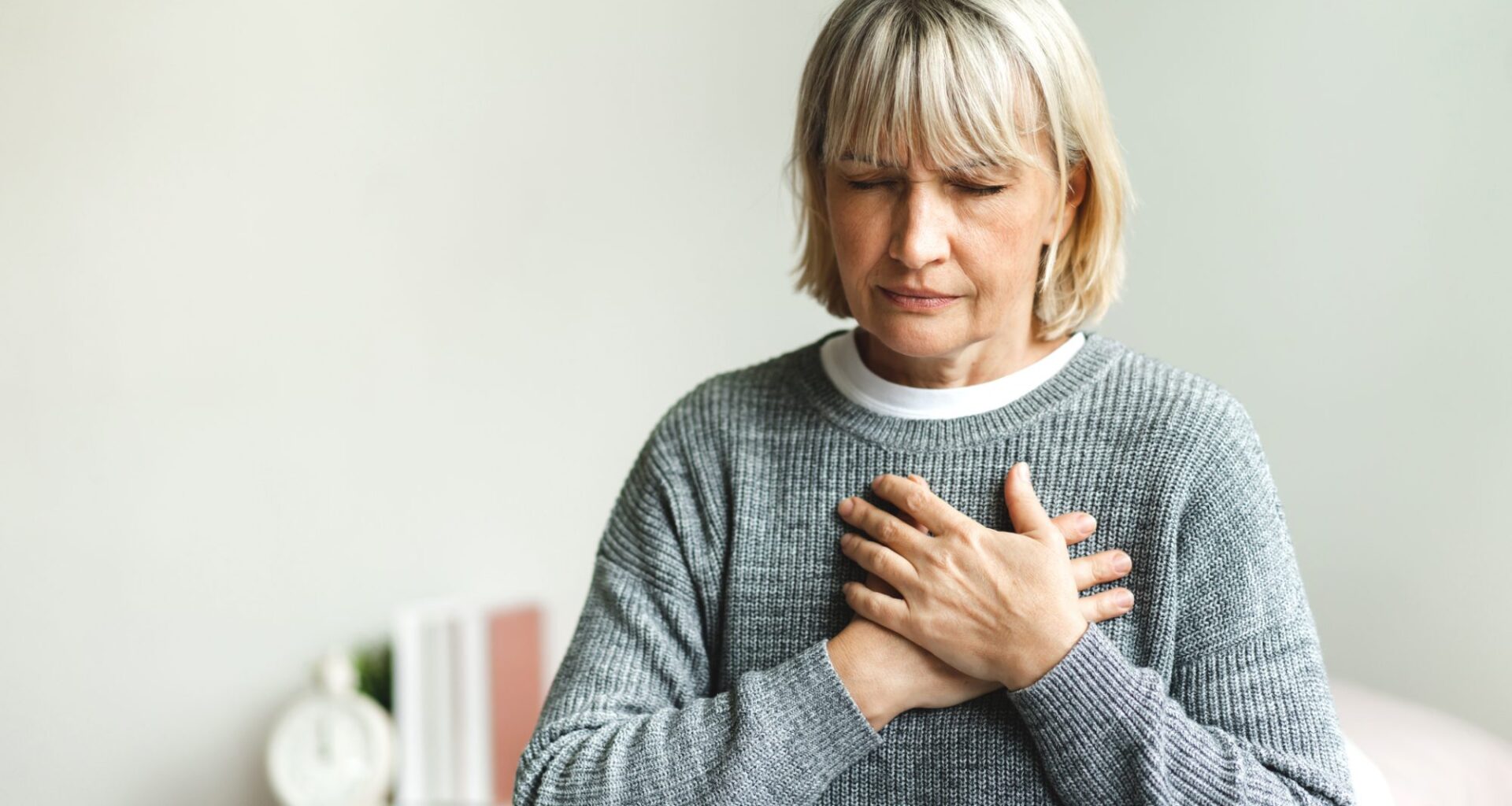 Senior adult elderly women sit on bed with chest pain suffering from heart attack in the bedroom.Healthcare and medical concept
