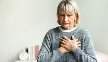 Senior adult elderly women sit on bed with chest pain suffering from heart attack in the bedroom.Healthcare and medical concept