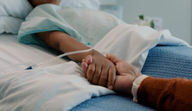 Hospital, holding hands and kid in bed with love, support and care in clinic after surgery. Child, healthcare and cancer patient with empathy, kindness and caregiver with compassion with help