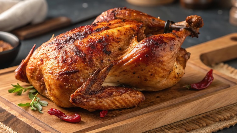 Whole roasted chicken on a wooden cutting board