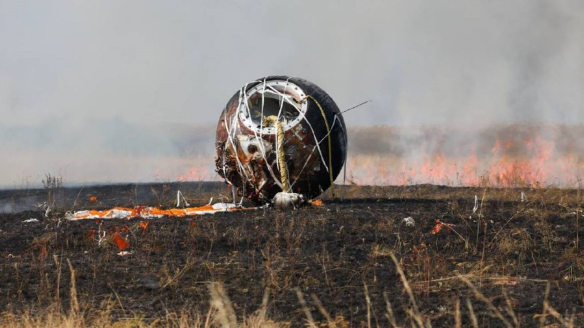 The Bion-M No. 2 descent module, a round metal ball sits next to its deployed parachute