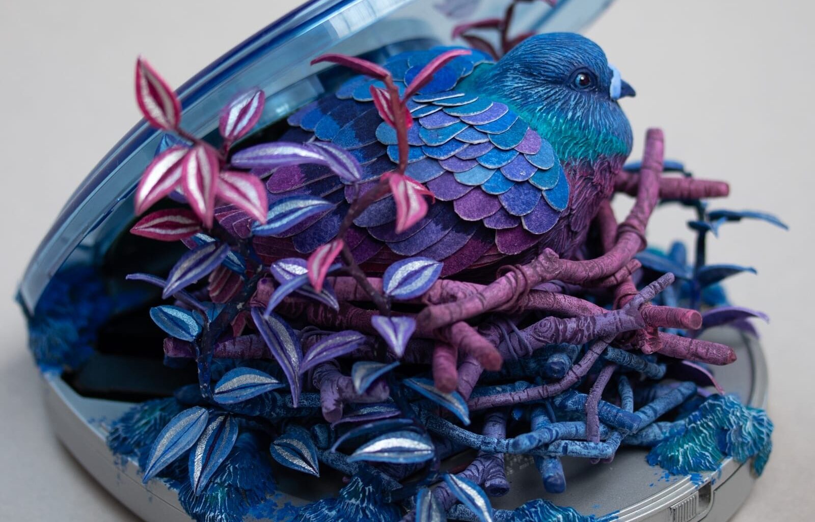 a sculpture by Stéphanie Kilgast of a colorful bird nesting inside of a portable CD player