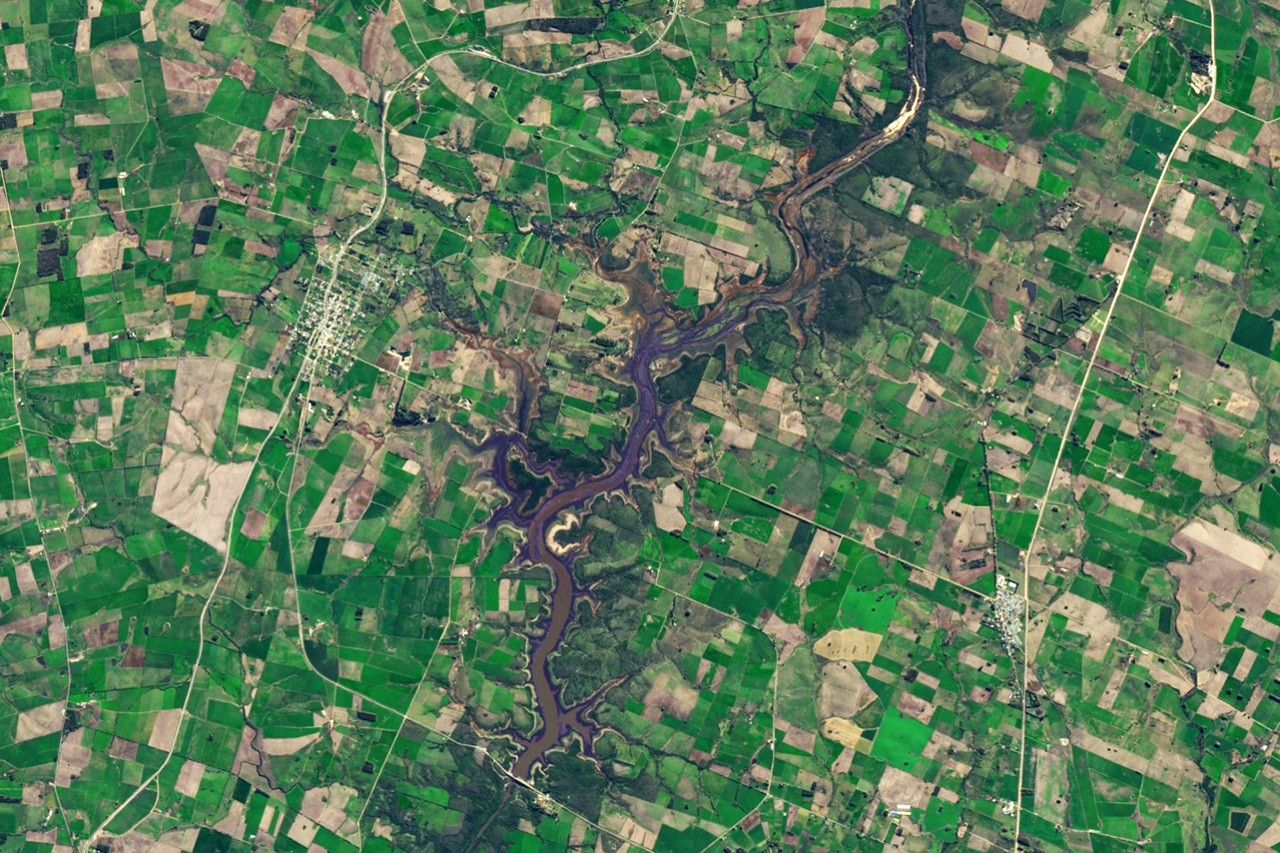 image of landscape with farmed fields surrounding a dammed river filled with water.