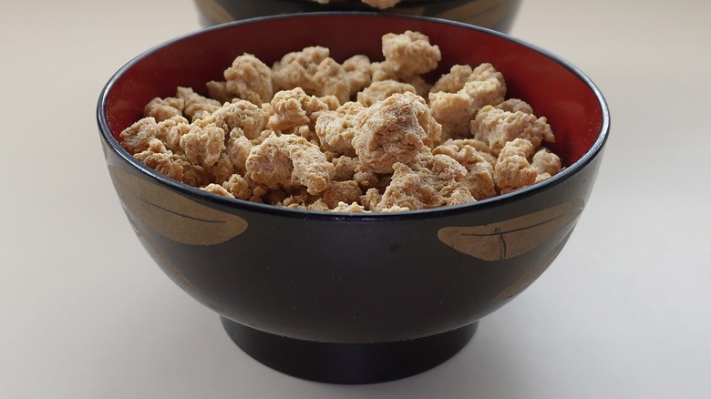 Dried pieces of soy meat in a black and red bowl
