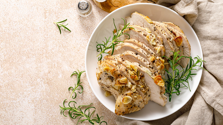 Sliced turkey breast with garnish in a white bowl