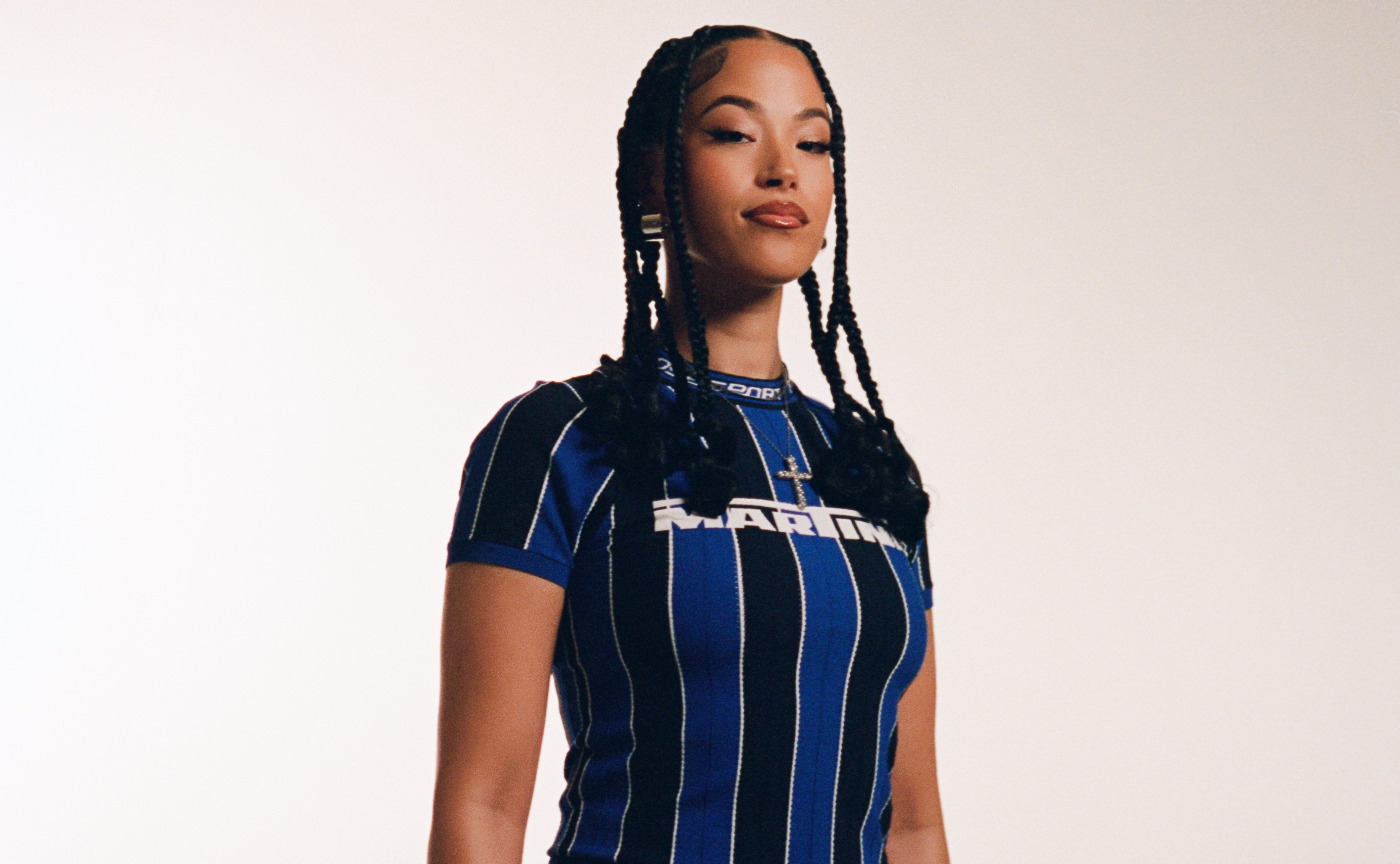 Jazzy, a woman with braided hair, wearing a blue and black striped shirt and camouflage pants.