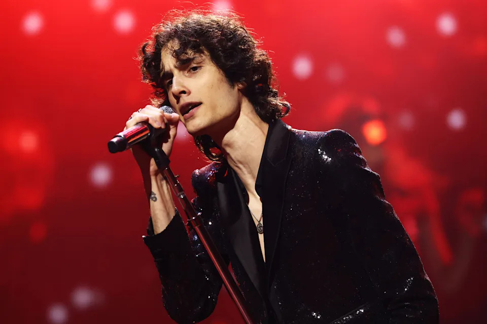 Sombr holds a microphone as he sings onstage.