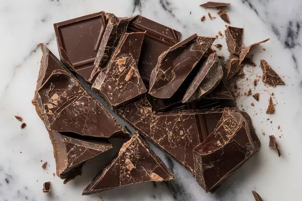 a marble surface with chunks and shavings of dark chocolate
