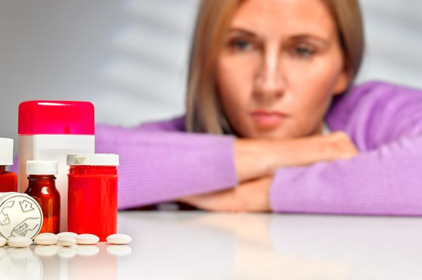 A woman looking at pill bottles