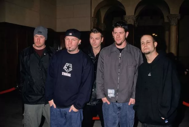 American rock band Limp Bizkit (American bassist Sam Rivers, wearing a black jacket, khaki trousers and a grey beanie, American singer, songwriter, rapper and film director Fred Durst, who wears a black 'Tribal' sweatshirt and reversed baseball cap, Latvian-American turntablist and music producer DJ Lethal, American guitarist Wes Borland, in a grey zip-front jacket and jeans, and American drummer John Otto, in a black hoodie) attend the MTV 'TRL' (Total Request Live) portrait photoshoot at the Park Plaza Hotel in Los Angeles, California, 21st February 2000