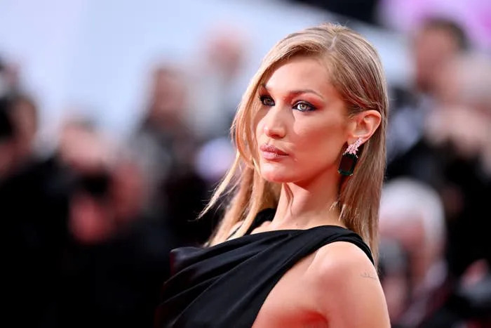 Bella Hadid in elegant draped dress with statement earrings on a red carpet at a formal event
