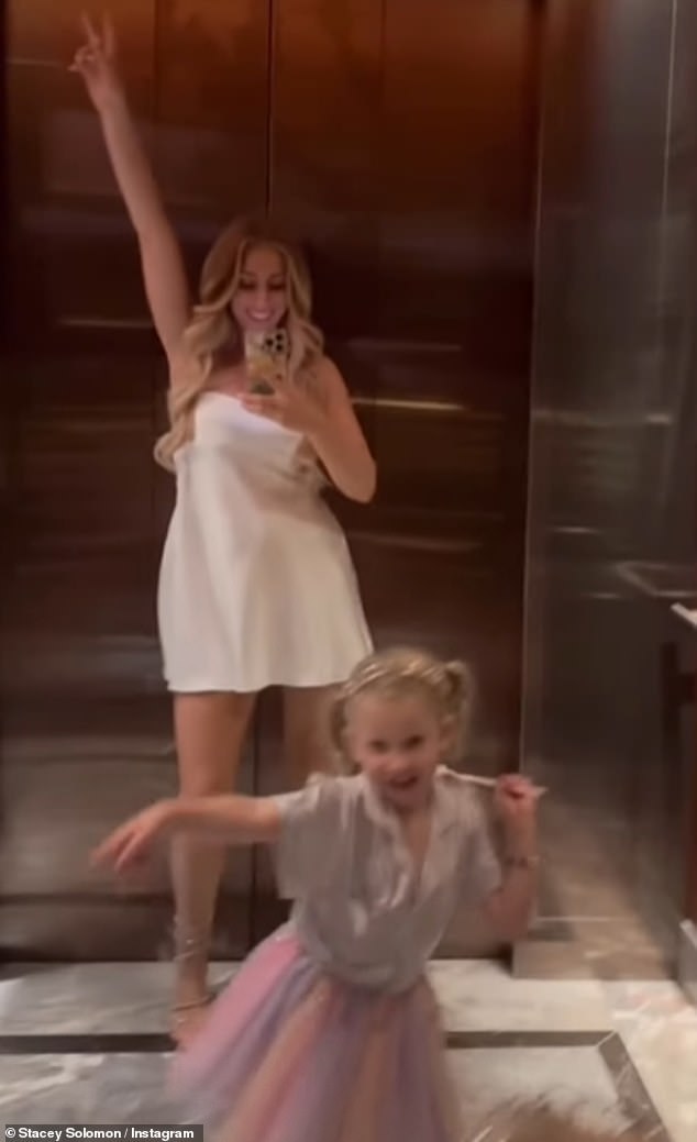 She showed off her amazing figure as she posed for a mirror selfie while her little girl excitedly danced around wearing a colourful skirt, fairy wings and a birthday headband