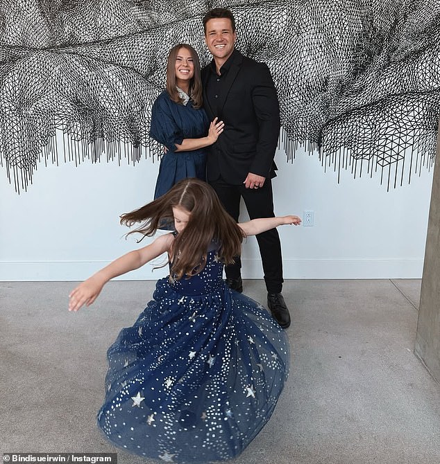 The Wildlife Warrior was unrecognisable on Tuesday as she dressed to the nines to cheer on her brother Robert Irwin at the Dancing With The Stars US live show. (Pictured: Bindi Irwin, Chandler Powell and their daughter Grace)