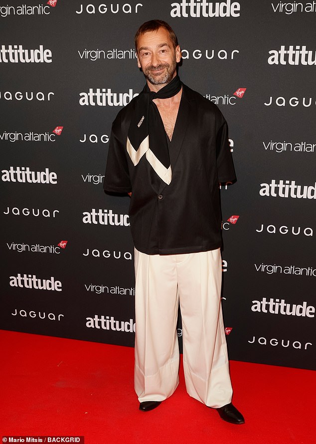 Actor and columnist Charlie Condou put on a quirky display in a black satin blazer-style shirt, baring his chest